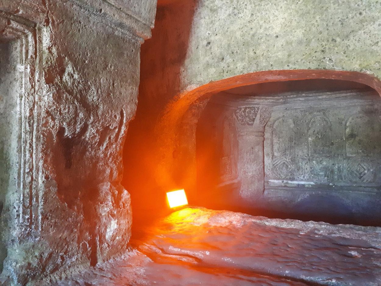 Aya Nikola Manastırı'nın kayaya oyulmuş, turuncu ışıkla aydınlanmış iç mekânı